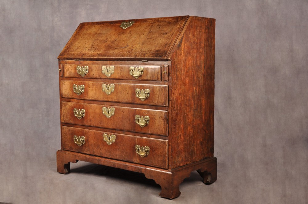 An early eighteenth-century walnut bureau with a sloping fall front, four drawers, decorative brass handles, and bracket feet. View XIII