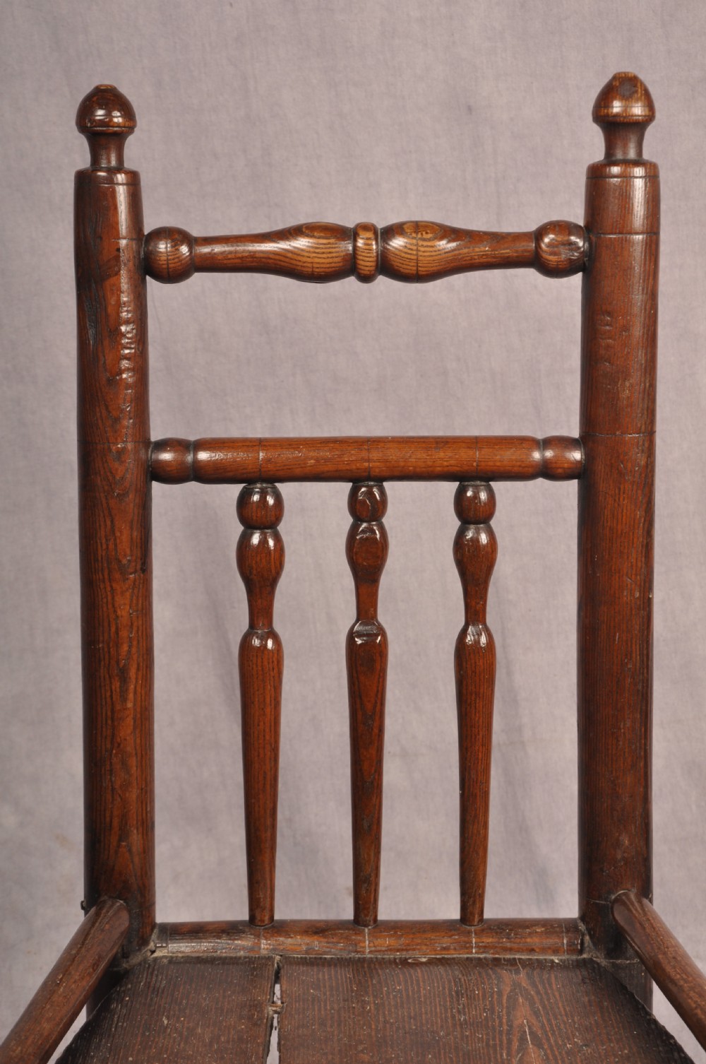 A near pair of dark 17th-century turned ash chairs with spindle backrests, turned stretchers, panel seats, and top finials. View IX