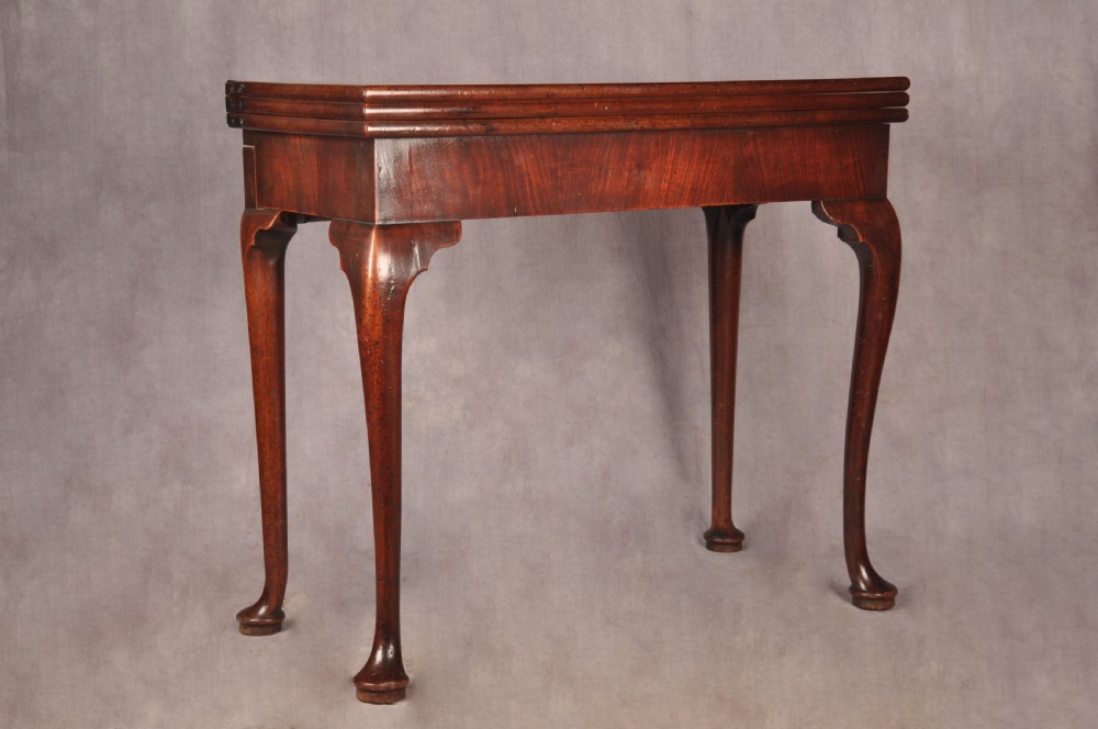An 18th-century mahogany triple-top card table resting on four cabriole legs with pad feet.