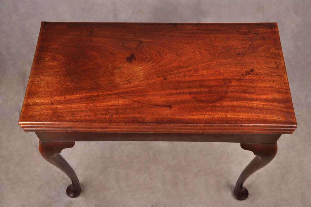 An 18th-century mahogany triple-top card table resting on four cabriole legs with pad feet. View V