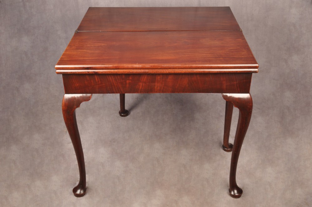 An 18th-century mahogany triple-top card table resting on four cabriole legs with pad feet. View XVIII
