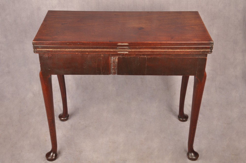 An 18th-century mahogany triple-top card table resting on four cabriole legs with pad feet. View XIX