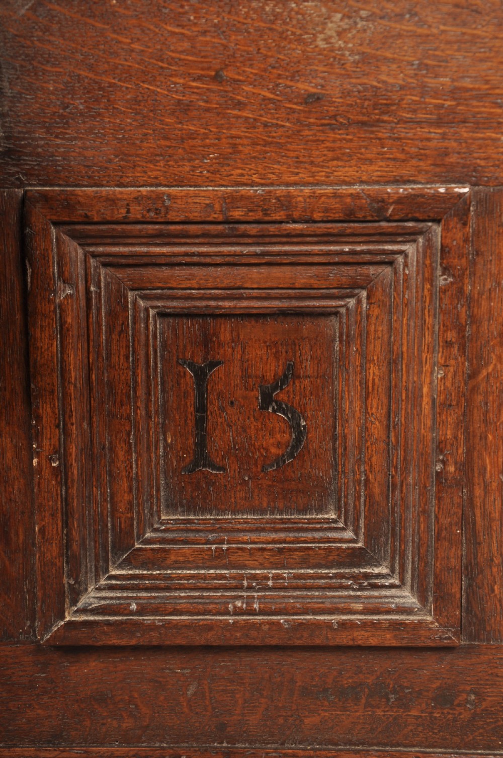 A dark oak Elizabethan coffer featuring four carved recessed panels inscribed with initials and the year 1589, secured with a central iron lock. View III
