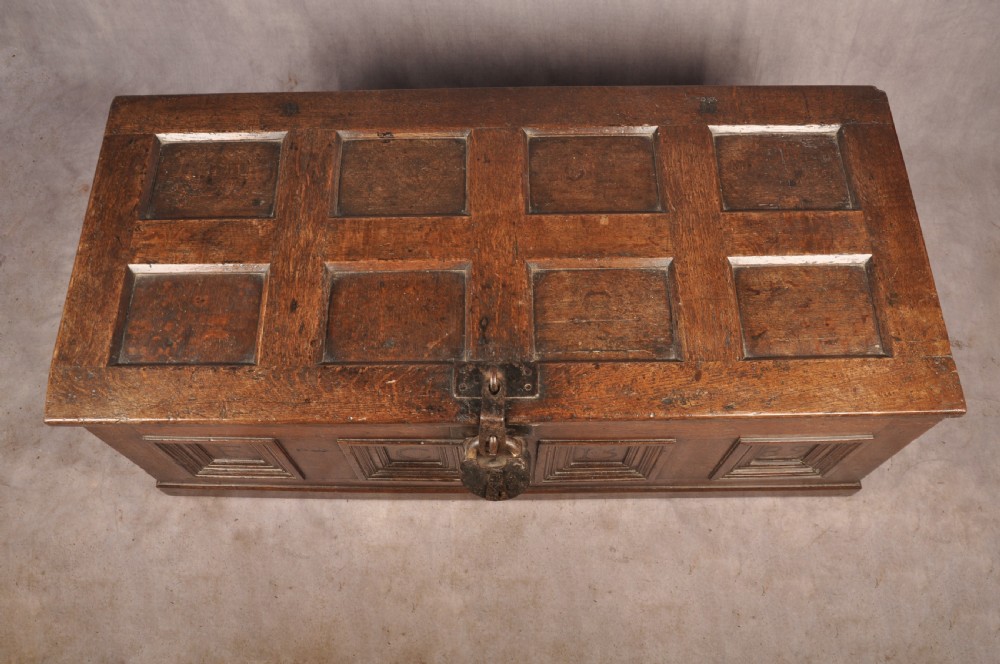 A dark oak Elizabethan coffer featuring four carved recessed panels inscribed with initials and the year 1589, secured with a central iron lock. View VI