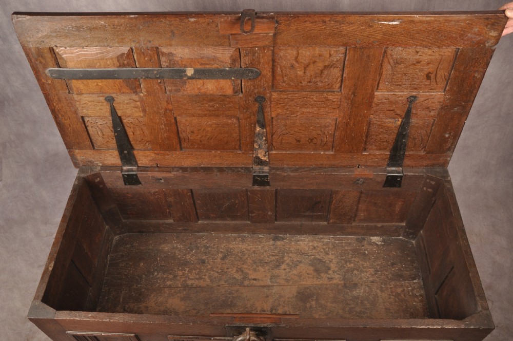 A dark oak Elizabethan coffer featuring four carved recessed panels inscribed with initials and the year 1589, secured with a central iron lock. View IX