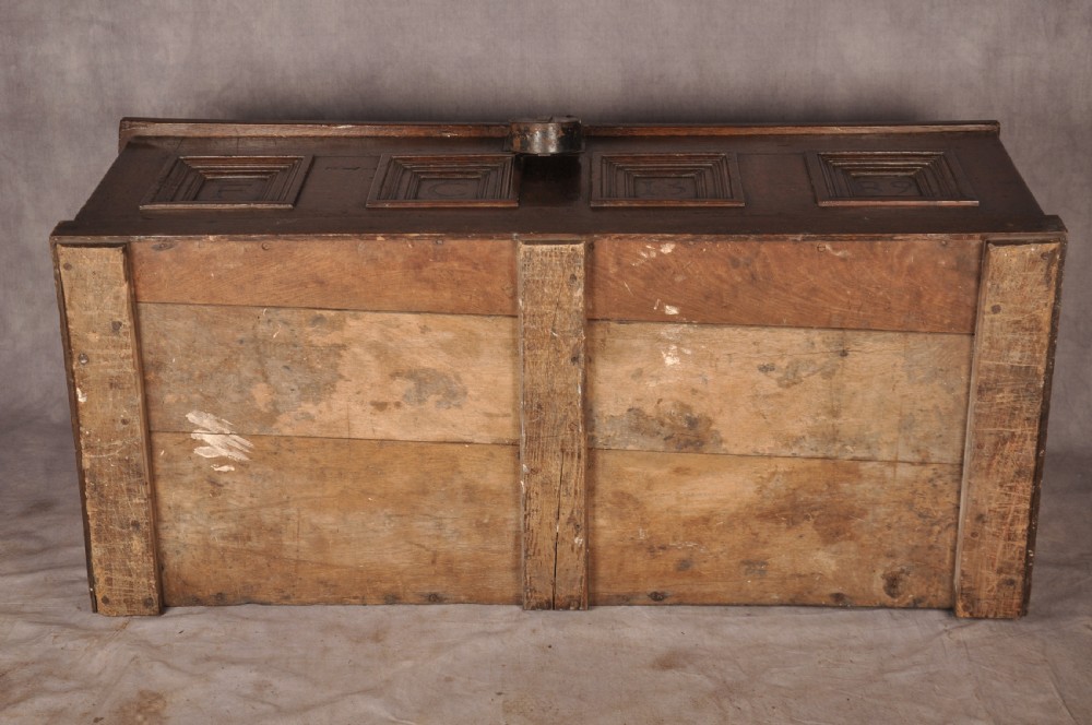 A dark oak Elizabethan coffer featuring four carved recessed panels inscribed with initials and the year 1589, secured with a central iron lock. View X