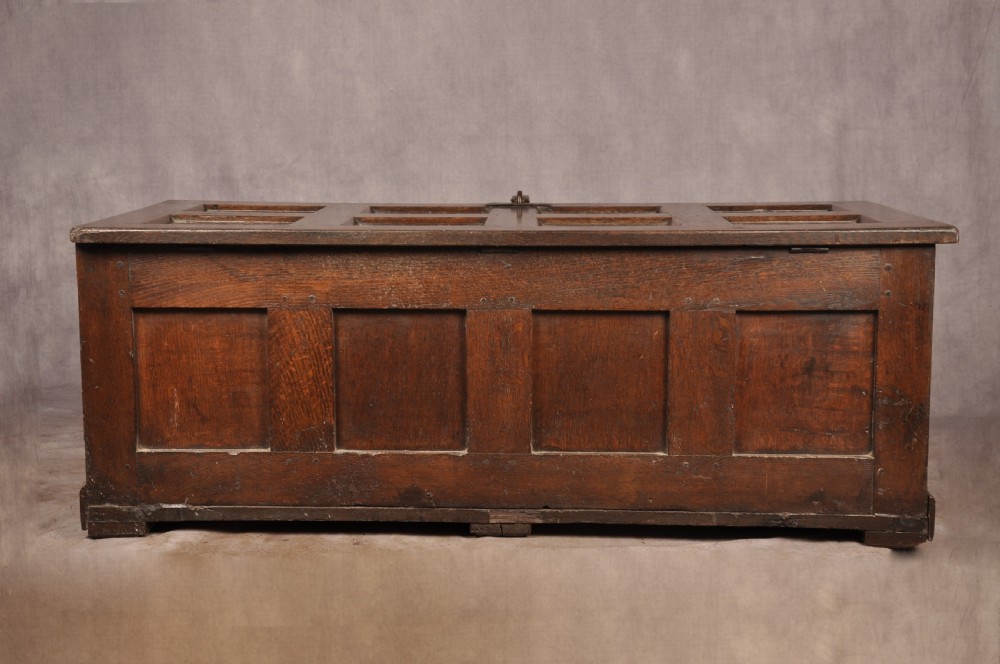 A dark oak Elizabethan coffer featuring four carved recessed panels inscribed with initials and the year 1589, secured with a central iron lock. View XI