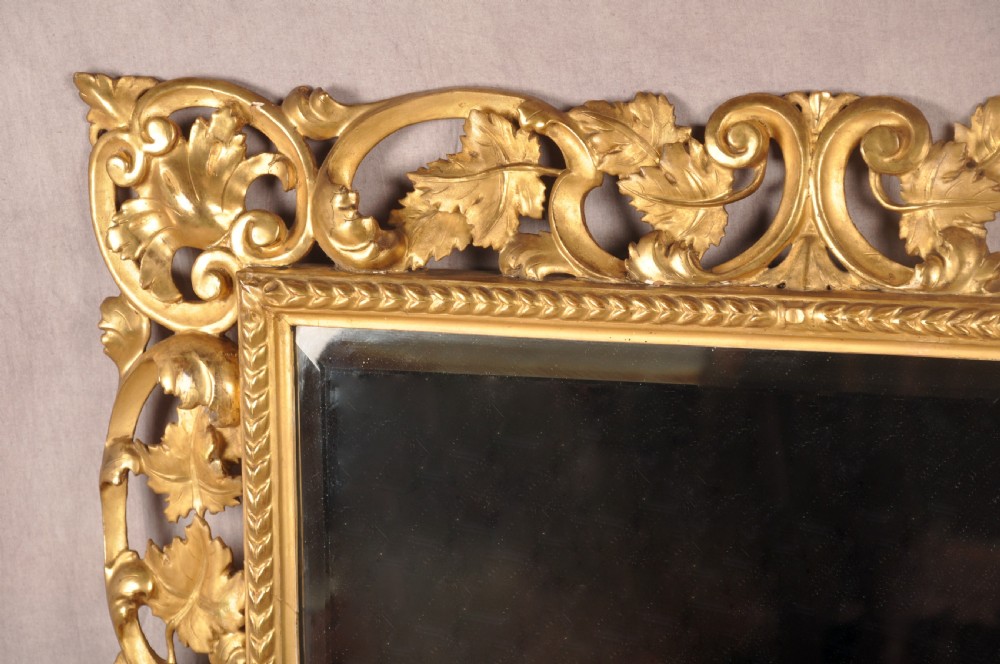 An early nineteenth-century rectangular wall mirror set within a deeply carved Florentine giltwood frame featuring openwork foliage, scrolls, and a beaded inner edge. View II