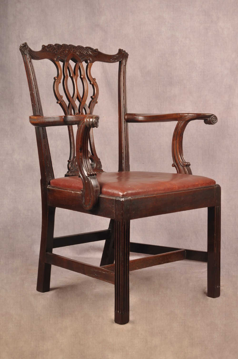 An 18th-century Chippendale mahogany armchair featuring an intricately carved Gothic tracery back splat, out-swept armrests, a brown leather seat, and square legs. View II
