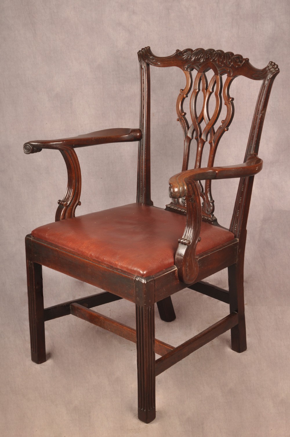 An 18th-century Chippendale mahogany armchair featuring an intricately carved Gothic tracery back splat, out-swept armrests, a brown leather seat, and square legs. View III