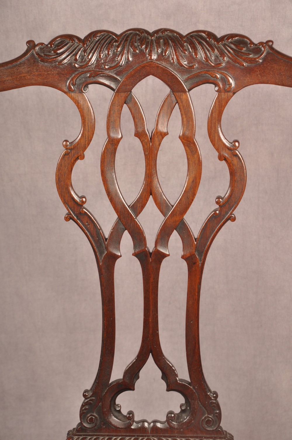 An 18th-century Chippendale mahogany armchair featuring an intricately carved Gothic tracery back splat, out-swept armrests, a brown leather seat, and square legs. View VI