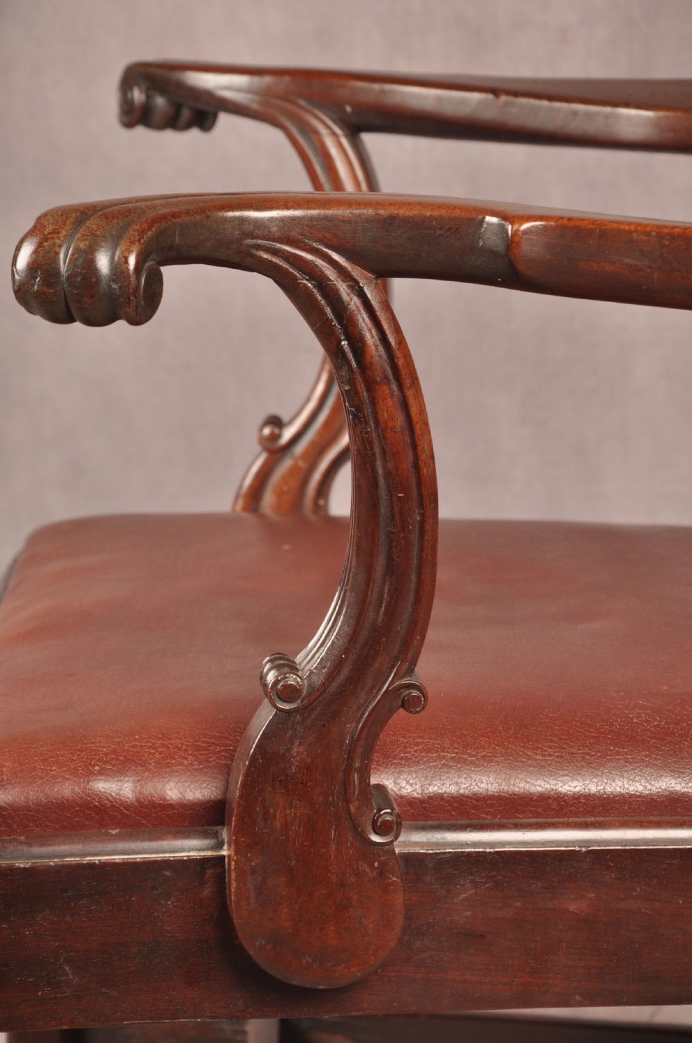 An 18th-century Chippendale mahogany armchair featuring an intricately carved Gothic tracery back splat, out-swept armrests, a brown leather seat, and square legs. View IX