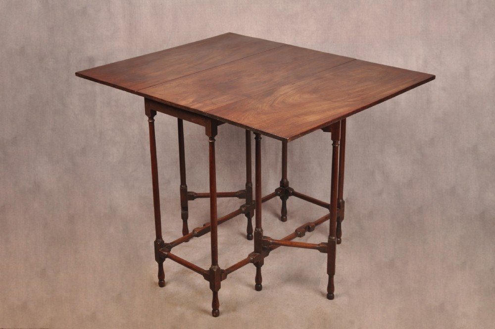 An 18th-century mahogany drop-leaf spider table featuring slender turned legs, cross stretchers, and two fold-out side flaps.