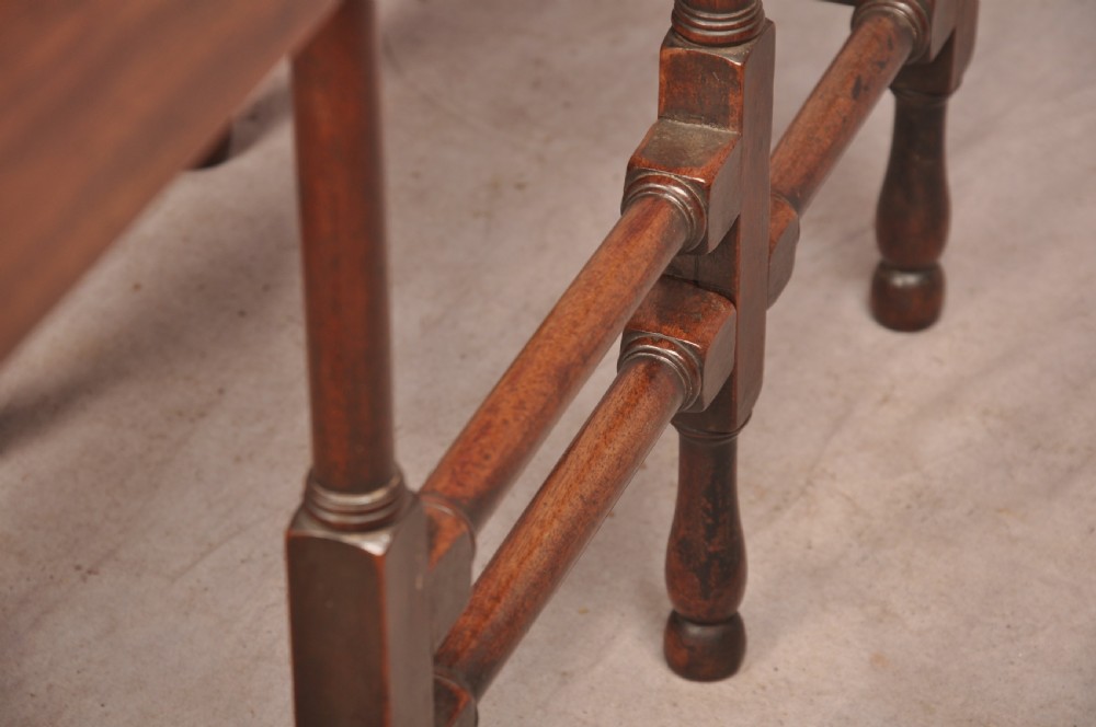An 18th-century mahogany drop-leaf spider table featuring slender turned legs, cross stretchers, and two fold-out side flaps. View X