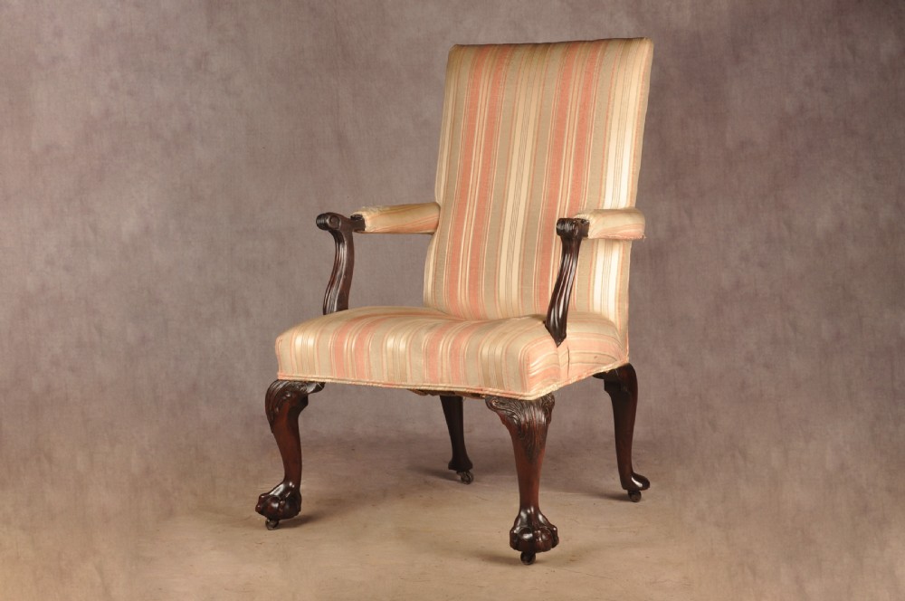 An 18th-century mahogany library chair upholstered in striped pink and cream fabric, featuring hand-carved cabriole front legs with ball-and-claw feet.