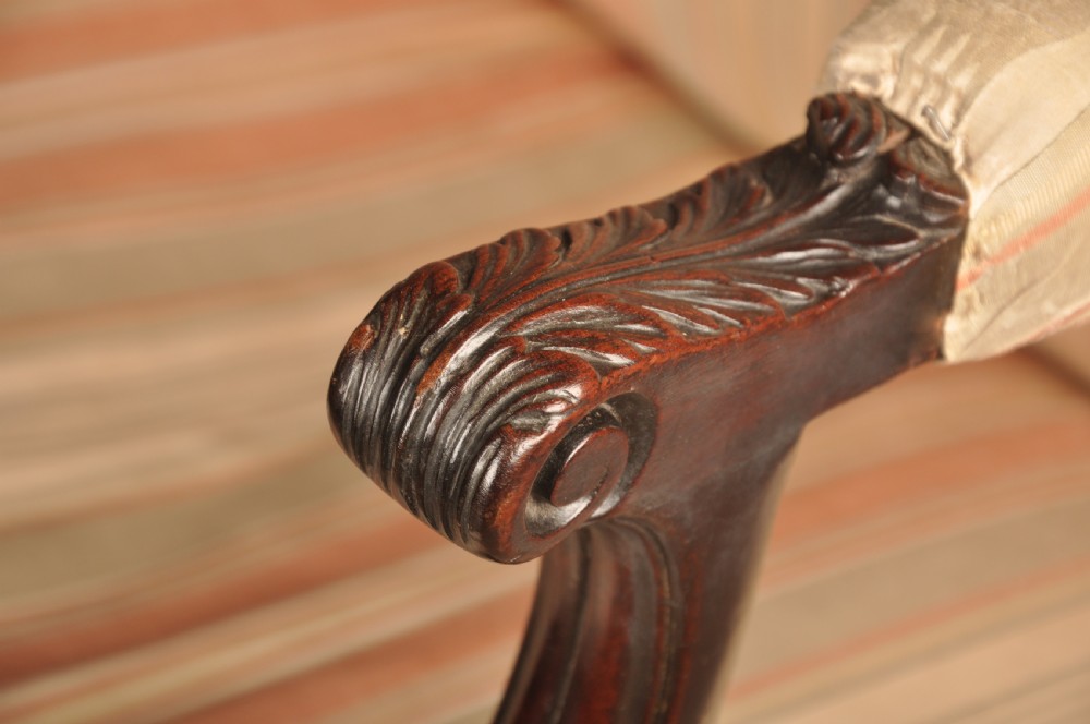 An 18th-century mahogany library chair upholstered in striped pink and cream fabric, featuring hand-carved cabriole front legs with ball-and-claw feet. View V
