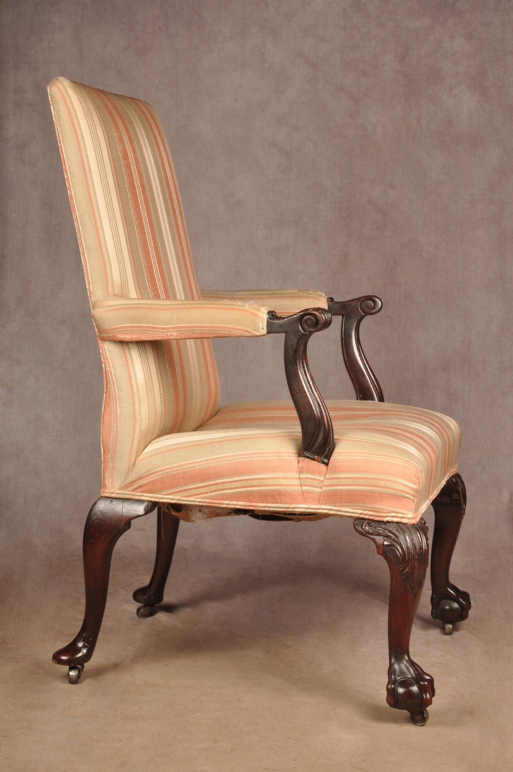 An 18th-century mahogany library chair upholstered in striped pink and cream fabric, featuring hand-carved cabriole front legs with ball-and-claw feet. View IX