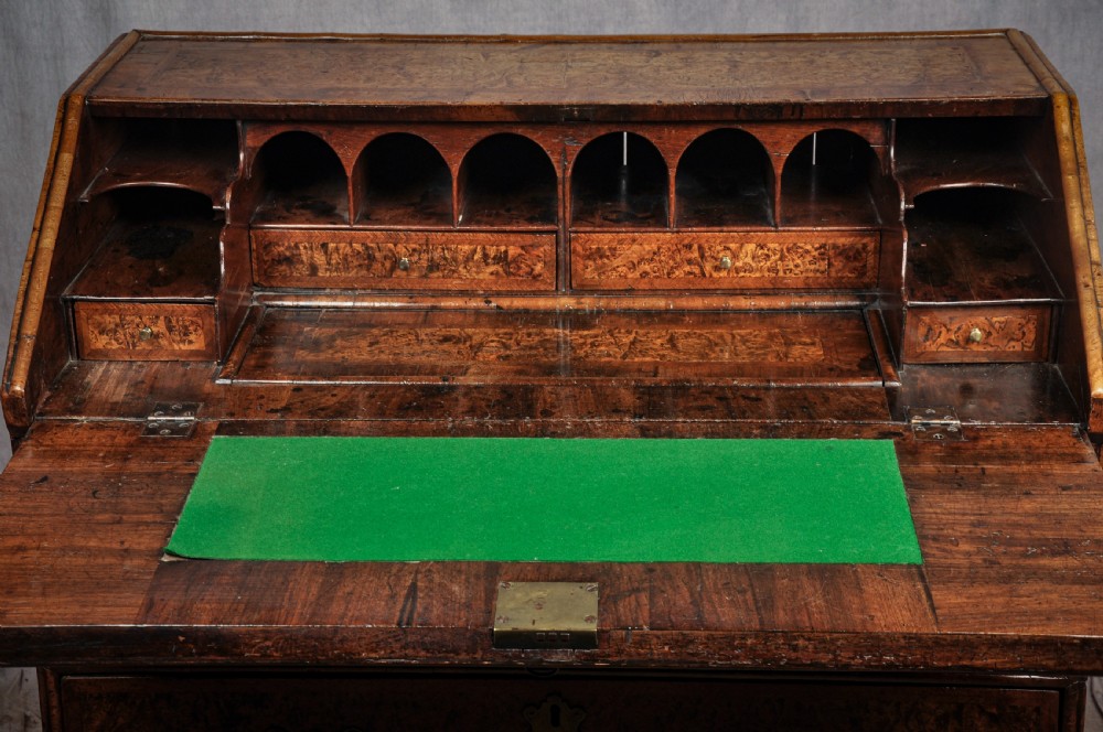 A late 17th-century slant-front bureau featuring highly figured mulberry veneer, brass drop handles, keyhole escutcheons, and four drawers resting on bracket feet. View V