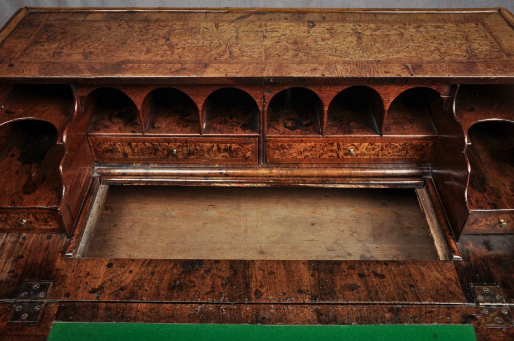 A late 17th-century slant-front bureau featuring highly figured mulberry veneer, brass drop handles, keyhole escutcheons, and four drawers resting on bracket feet. View VI