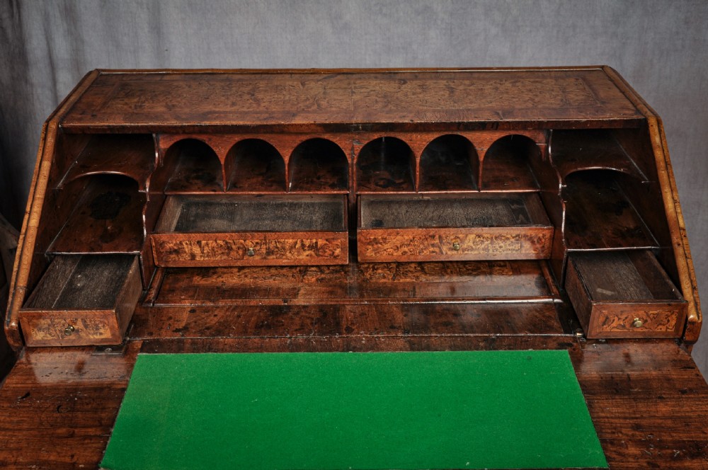 A late 17th-century slant-front bureau featuring highly figured mulberry veneer, brass drop handles, keyhole escutcheons, and four drawers resting on bracket feet. View VII