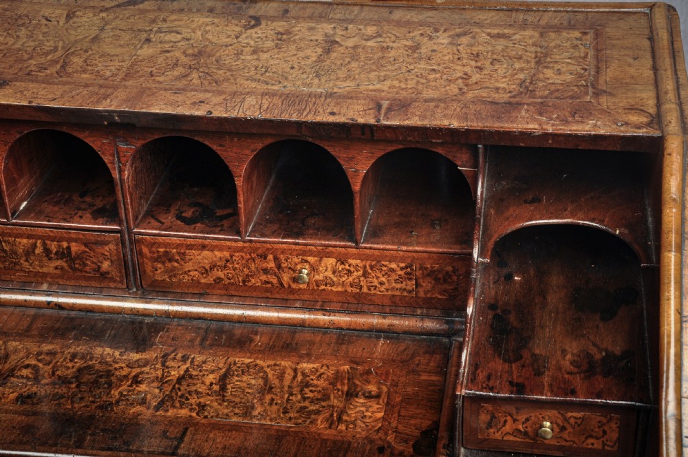 A late 17th-century slant-front bureau featuring highly figured mulberry veneer, brass drop handles, keyhole escutcheons, and four drawers resting on bracket feet. View VIII