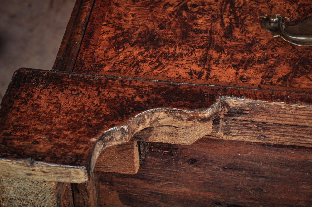 A late 17th-century slant-front bureau featuring highly figured mulberry veneer, brass drop handles, keyhole escutcheons, and four drawers resting on bracket feet. View XVII