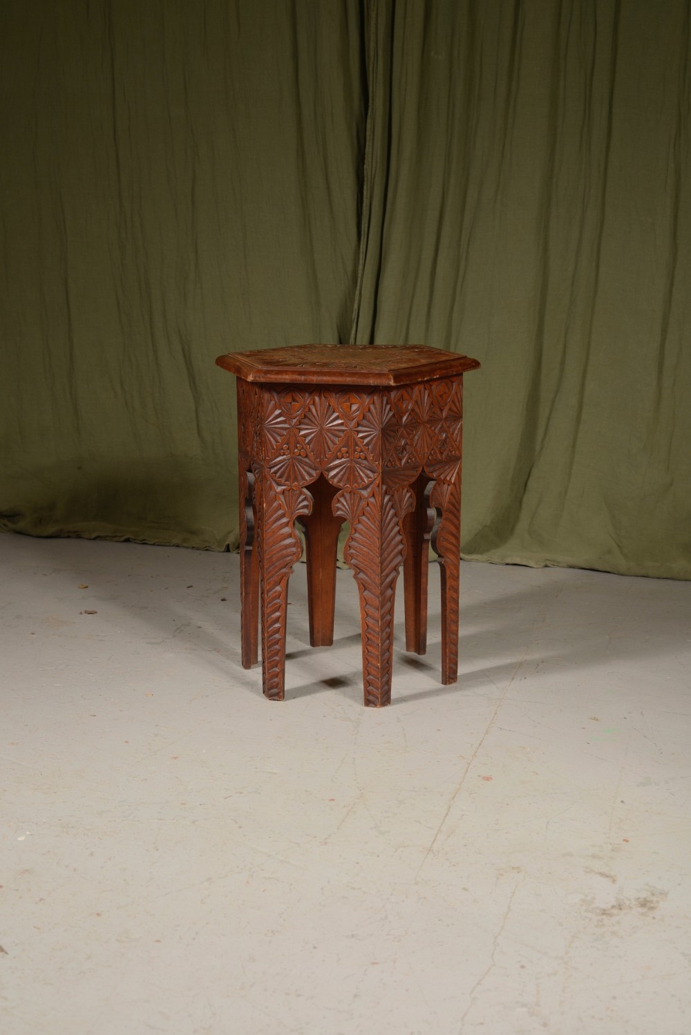 An octagonal pine side table featuring geometric chip-carved patterns across the apron and shaped legs.