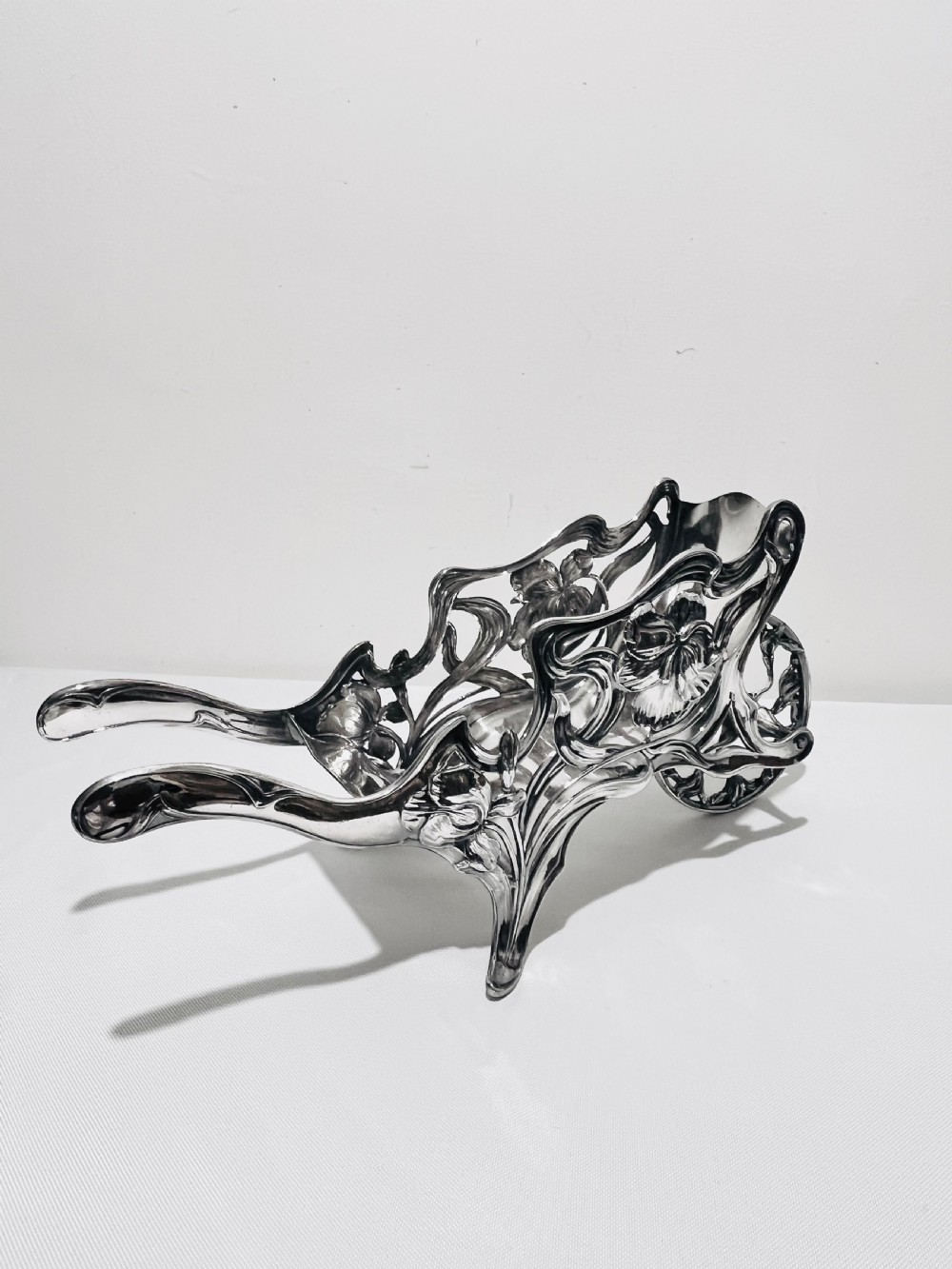 An Art Nouveau silver-plated wine wagon shaped like a stylized wheelbarrow with intricate botanical openwork and flowing organic curves. View VII