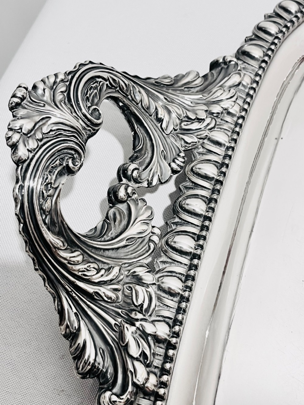 A rectangular silver-plated tray featuring ornate cast acanthus handles, a gadrooned rim, and an engraved heraldic coat of arms at the centre. View III