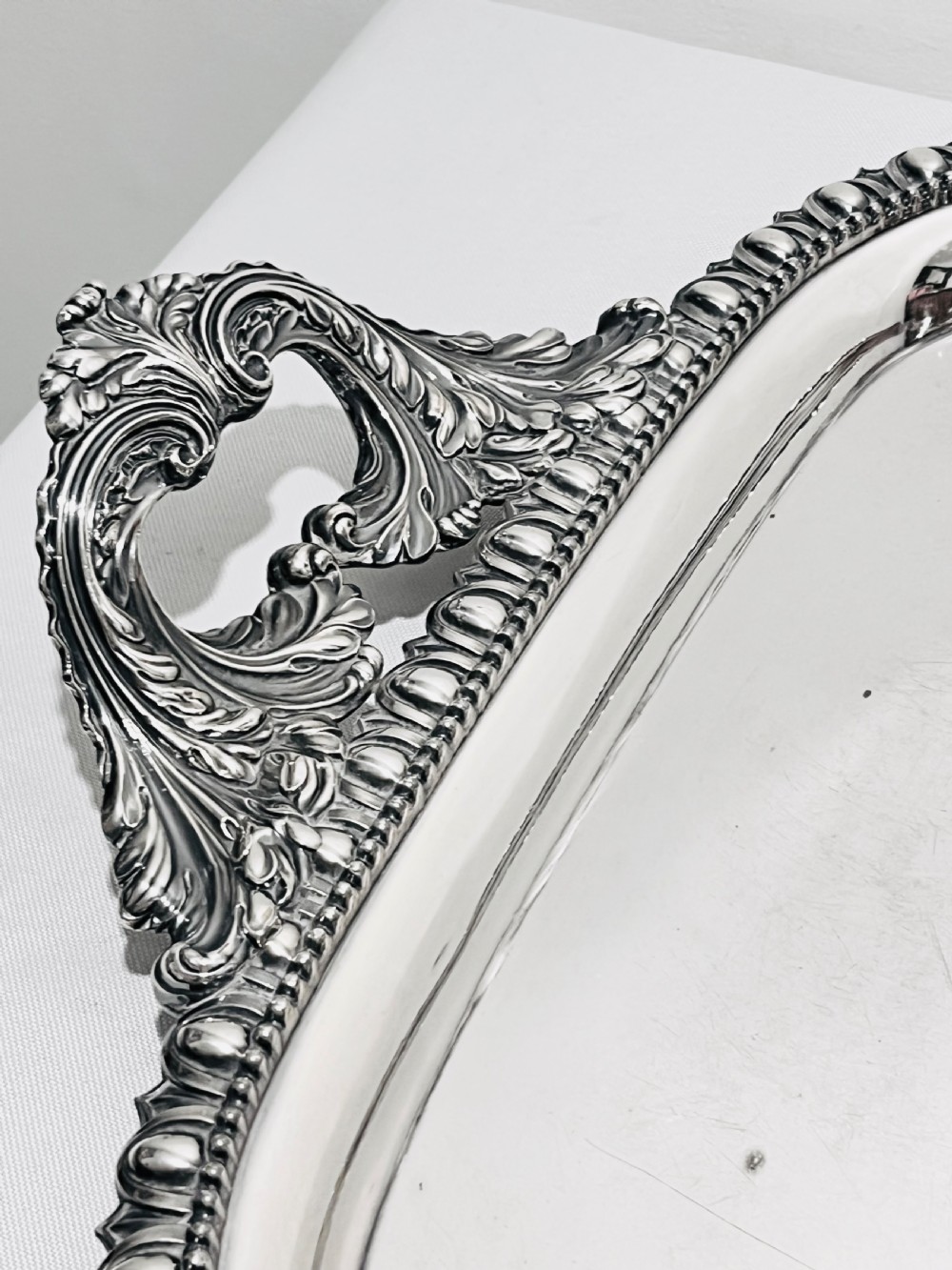 A rectangular silver-plated tray featuring ornate cast acanthus handles, a gadrooned rim, and an engraved heraldic coat of arms at the centre. View VI