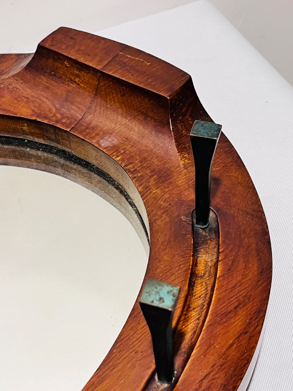 A Victorian horseshoe-shaped wooden wall mirror with bevelled glass and dark metal nail pegs along the frame. View III