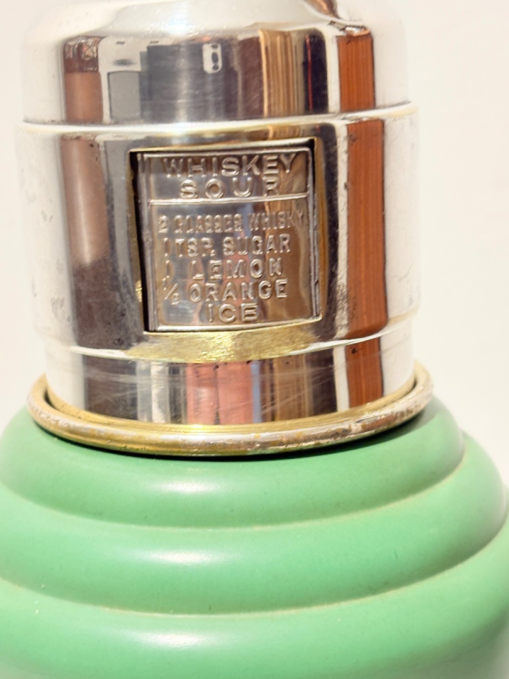 An Art Deco Master Incolor cocktail shaker featuring a green Bakelite body with silver-plated trim and a rotating recipe window cap. View III