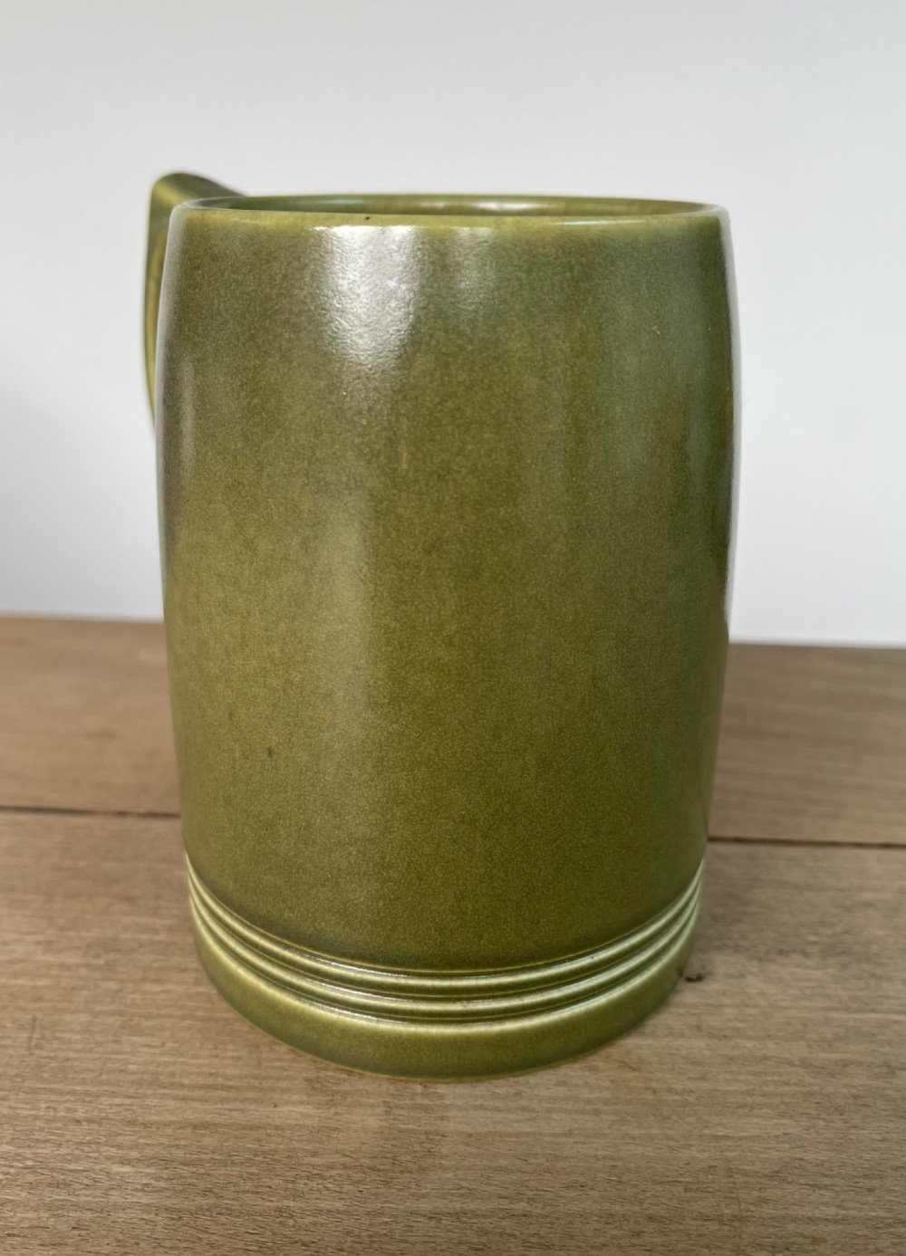 A green glazed Art Deco ceramic tankard featuring a geometric angular handle and subtle concentric ribbed detail around the base. View II