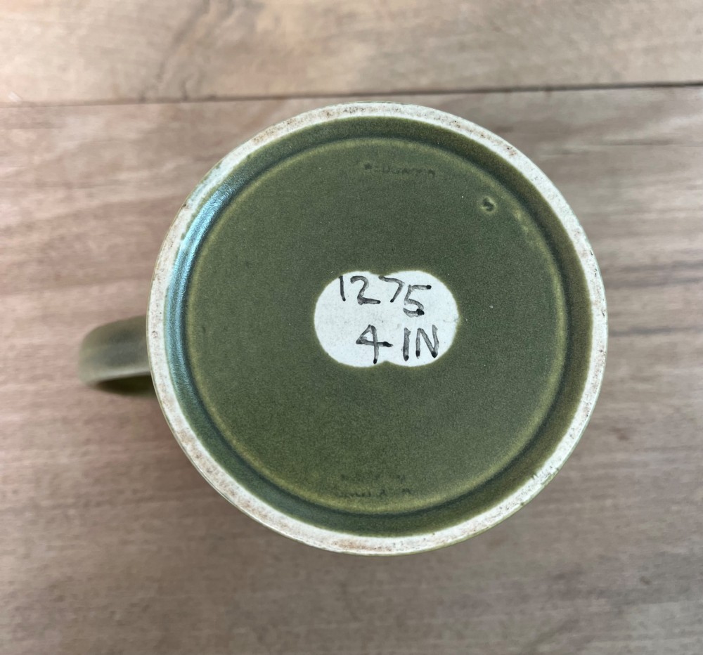 A green glazed Art Deco ceramic tankard featuring a geometric angular handle and subtle concentric ribbed detail around the base. View VI