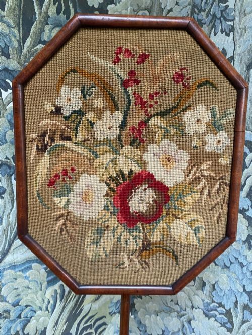 fig 1. An antique mahogany pole screen featuring an octagonal framed floral needlepoint panel supported by an adjustable slender stem and tripod base.