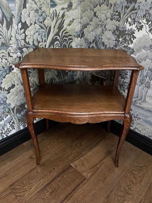 fig 1. An antique warm brown oak two-tier side table with shaped edges and slender cabriole legs.