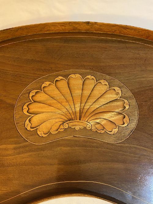 fig 1. A kidney-shaped antique mahogany serving tray featuring a central satinwood shell marquetry inlay and twin brass handles.