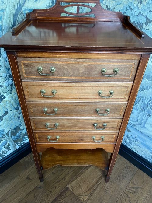 fig 1. A tall Edwardian mahogany music cabinet featuring five drop-front drawers with brass handles, boxwood line inlay, an open bottom shelf, and a top gallery rail.