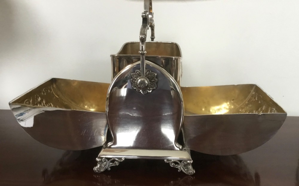 Victorian silver-plated mechanical rise and fall biscuit box with chased floral scrollwork, a pierced handle, and scroll feet. View III