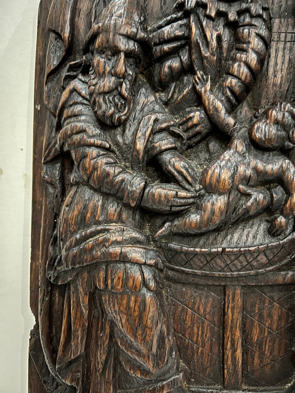 An arched dark oak panel featuring a high-relief hand carving of the circumcision of Christ with several figures. View II