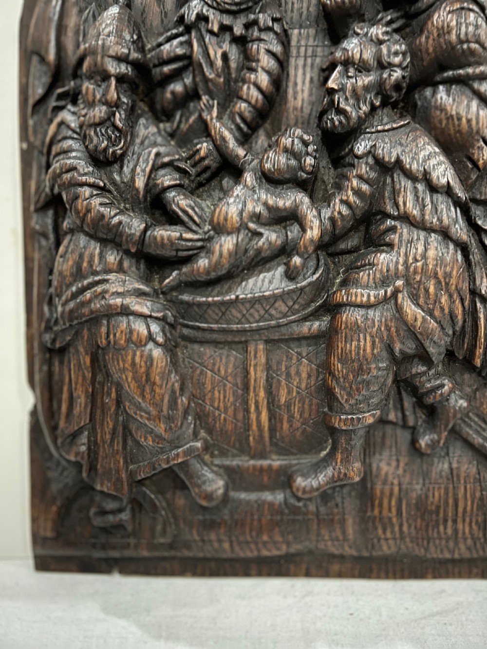 An arched dark oak panel featuring a high-relief hand carving of the circumcision of Christ with several figures. View III