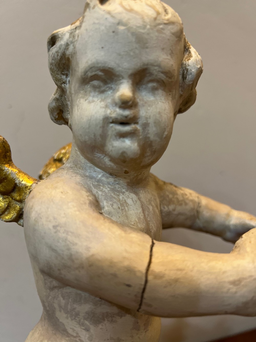 A pair of 18th-century carved wood polychrome putti featuring painted off-white figures with gilded wings and drapery, resting upon carved cloud bases. View V