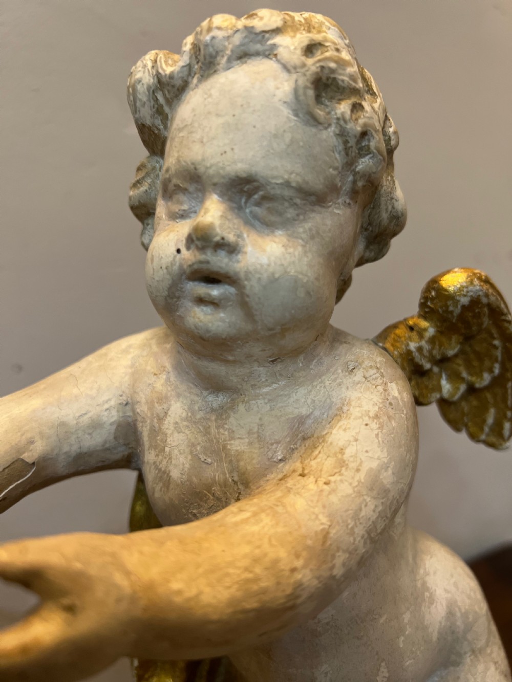 A pair of 18th-century carved wood polychrome putti featuring painted off-white figures with gilded wings and drapery, resting upon carved cloud bases. View VI