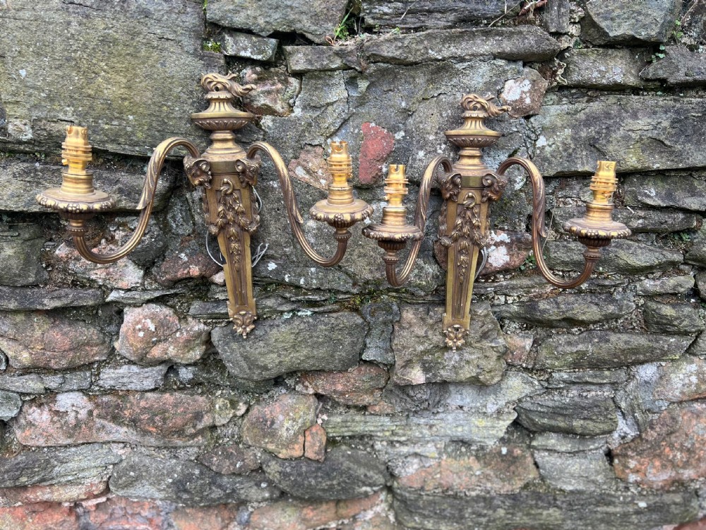 A pair of Edwardian cast brass twin-arm wall lights designed in the Neoclassical Adam style with urn finials and tapered backplates. View III
