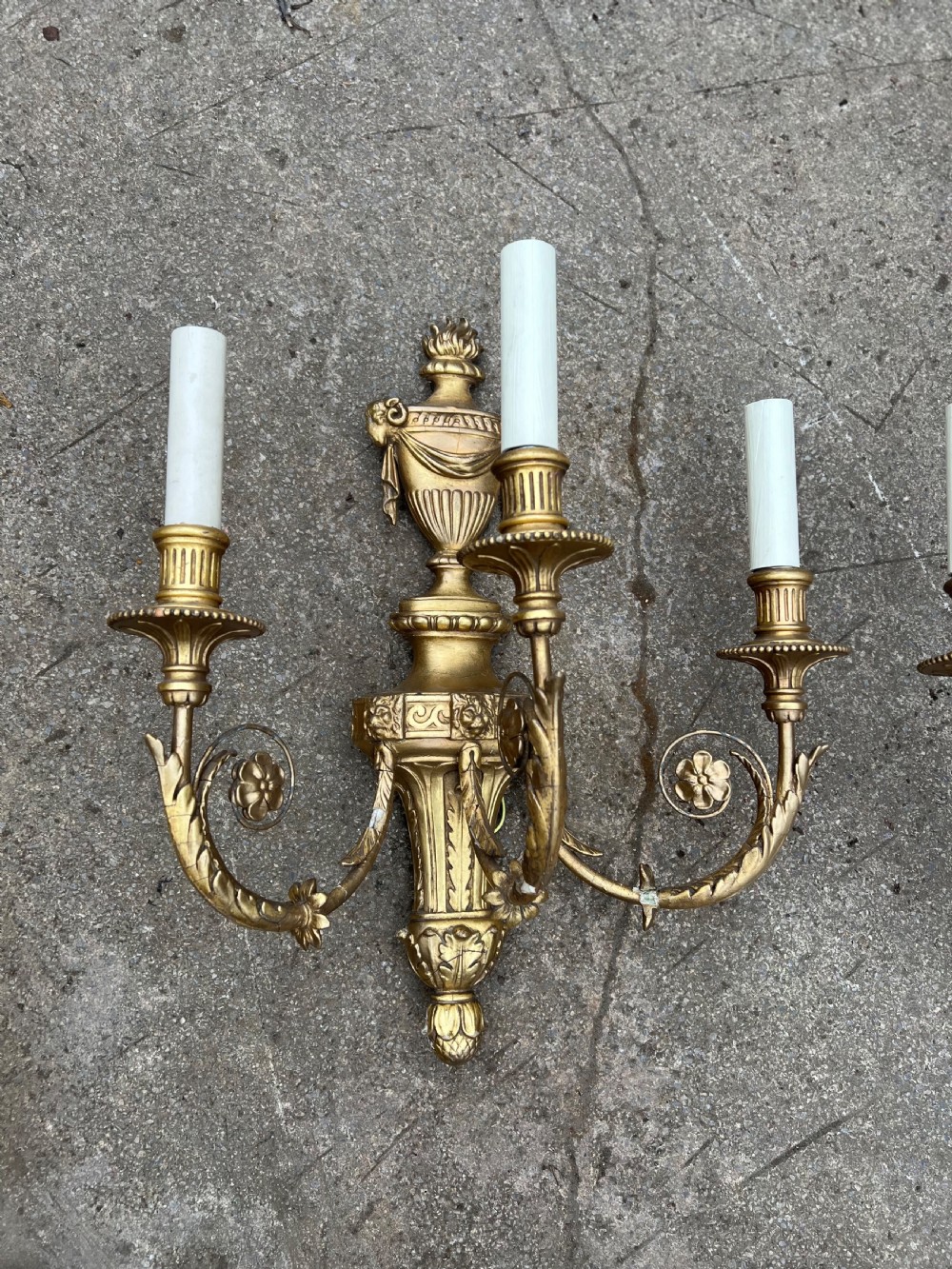 A pair of three-arm Neoclassical style giltwood and gesso wall sconces featuring urn backplates and foliage scrollwork. View II