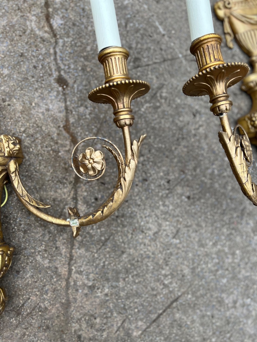 A pair of three-arm Neoclassical style giltwood and gesso wall sconces featuring urn backplates and foliage scrollwork. View III