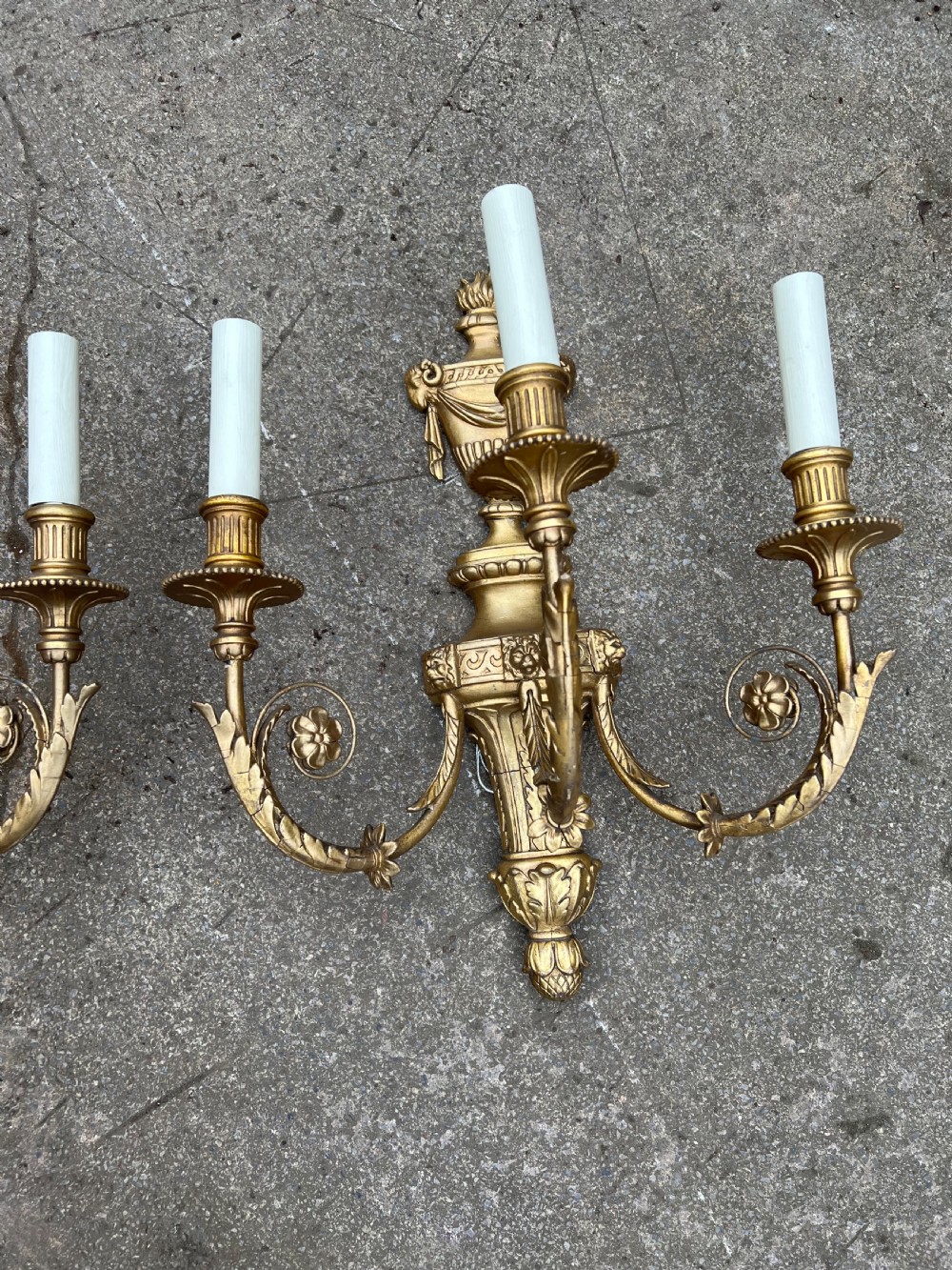 A pair of three-arm Neoclassical style giltwood and gesso wall sconces featuring urn backplates and foliage scrollwork. View IV
