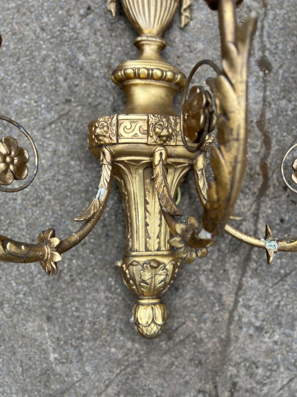 A pair of three-arm Neoclassical style giltwood and gesso wall sconces featuring urn backplates and foliage scrollwork. View V