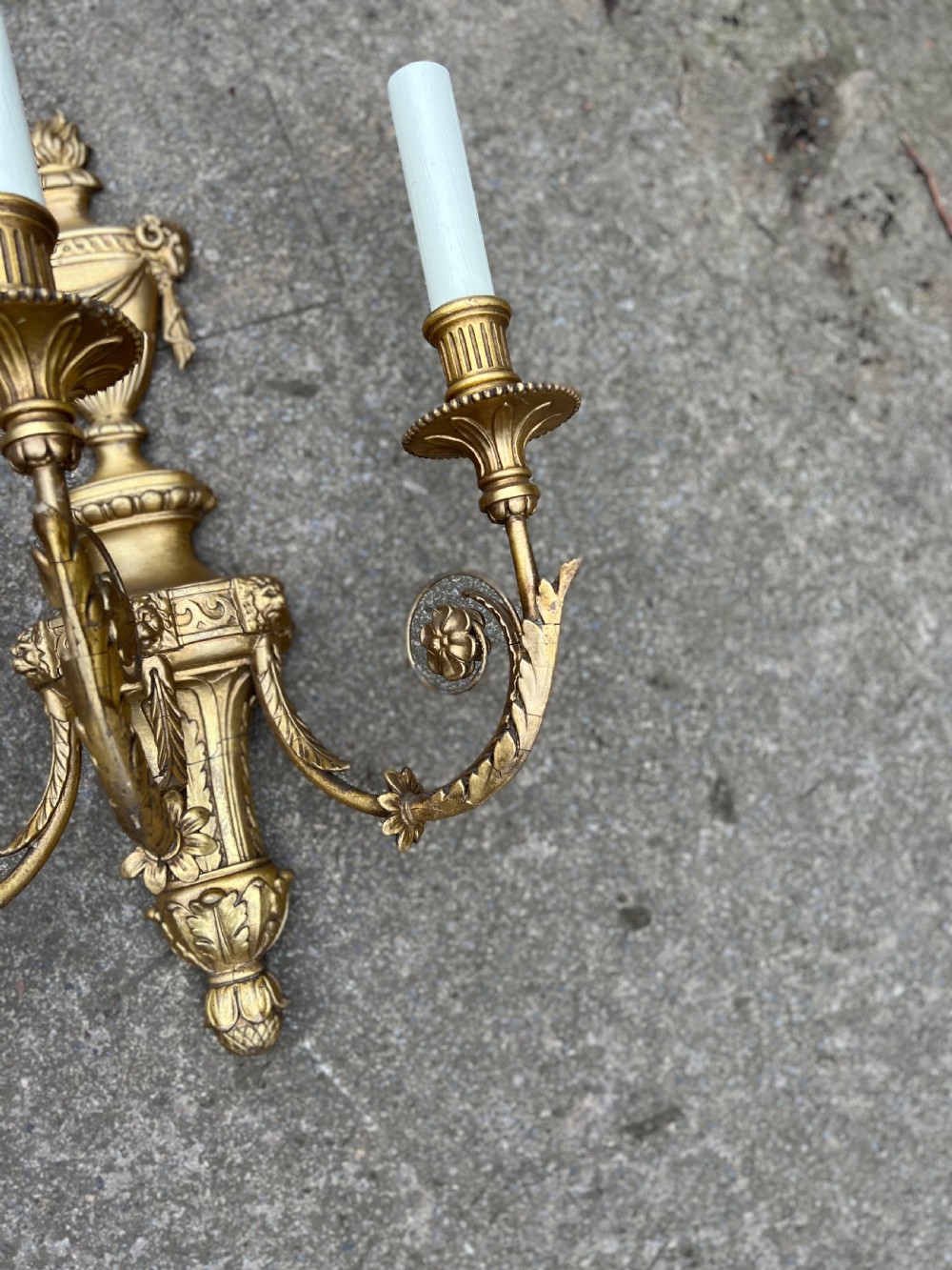 A pair of three-arm Neoclassical style giltwood and gesso wall sconces featuring urn backplates and foliage scrollwork. View VII