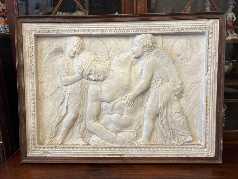 An off-white 19th-century plaster bas-relief panel depicting Christ supported by angels, framed within an inner egg-and-dart moulding and dark timber outer frame.